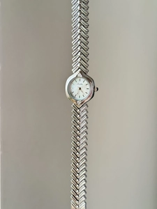Detail of the silver women's watch featuring a V-shaped fishbone metal link strap
