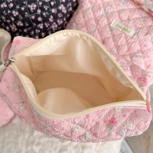 Close-up of pink quilted cosmetic bag with open zipper showing spacious inner lining