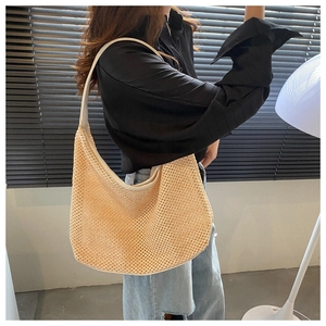 Detailed view of beige woven hobo bag with leather handles worn by a fashion model