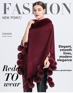 Close-up of burgundy knitted poncho featuring a faux fur collar and decorative pom-poms