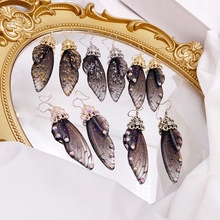 Macro shot of silver butterfly wing earrings with purple gradient and glitter detail