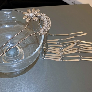 Detailed view of silver flower hair fork with long metal tassels and central pearl accent