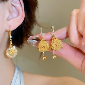 Detail of elegant gold rose earrings with crystal diamonds and mesh texture petals