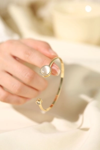 Detail of adjustable gold bangle featuring a spinning cat eye stone and zircon accents