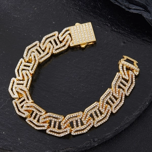 Close-up of golden iced-out Cuban link bracelet with crystals on a dark textured surface