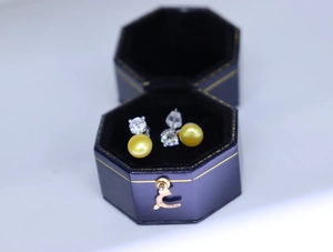 Detail view of pearl and zircon stud earrings inside a blue velvet octagonal jewelry box