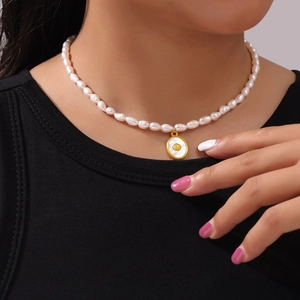 Elegant freshwater pearl necklace with gold oval shell pendant worn on a female model