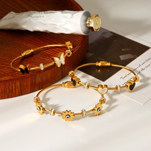 Detailed close-up of golden stainless steel bracelets with butterfly and heart charms