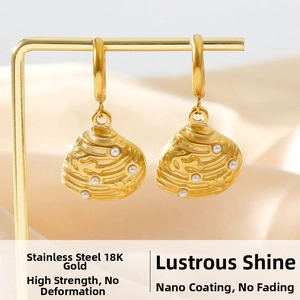 Close-up of 18K gold-plated shell earrings with white pearls on a silk background