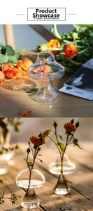 Detail of mushroom shaped clear glass vase with fresh orange roses on wooden table
