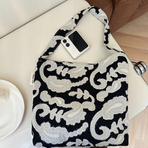 Detailed close-up of a black cotton tote bag with white floral embroidery and size reference