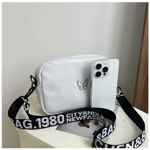 Detail view of white nylon small square bag with printed wide shoulder strap and metal logo