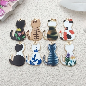 Close-up of eight diverse cat-shaped alloy charms with floral and striped oil drip patterns