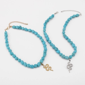 Detailed macro view of bohemian turquoise bead necklaces with snake shaped gold and silver charms