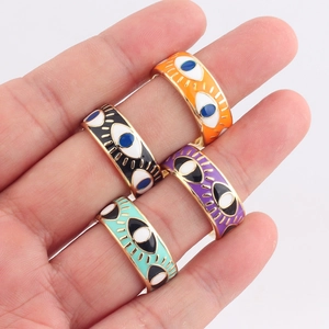 Detail of four gold evil eye rings with orange, black, purple, and blue enamel finish