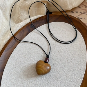 Detail of heart-shaped wooden pendant with natural grain and black wax rope necklace