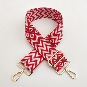 Detail of red and white geometric woven bag strap with golden metal swivel hooks