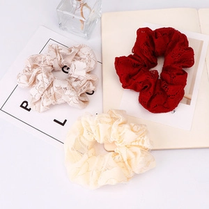 Three lace scrunchies in beige, apricot, and burgundy displayed on a white surface