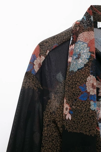 Close-up of semi-transparent black chiffon fabric with vintage floral and scroll patterns