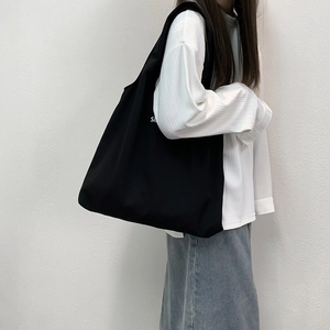 Grand sac cabas minimaliste en toile noire avec imprimé lettres porté à l'épaule