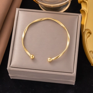 Polished Mobius twist open bangle in gold finish on a luxury jewelry box display