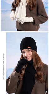 Detail of knitted winter set showing beanie with logo patch, fringe scarf and touchscreen gloves