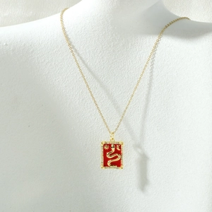 Close-up of a gold tarot card snake pendant necklace with red enamel and zircon accents