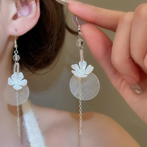Detail of silver floral earrings with shell petals and long chain tassels worn by a model
