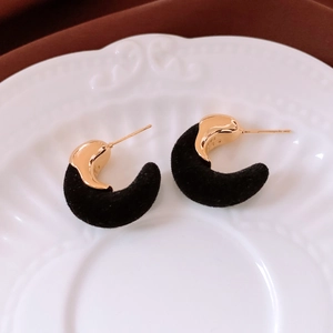 Détail des boucles d'oreilles en forme de C dorées 18K et velours noir sur plat décoré