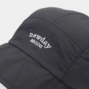 Detail of black quilted sun hat featuring white newday BEGINS embroidery and texture