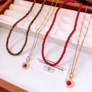 Macro detail of 18K gold plated tiger eye pendants and beaded necklaces on a display tray