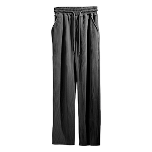 Detail of dark grey pleated fabric and elastic drawstring waistband on wide-leg trousers