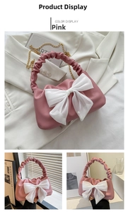 Detailed close-up of pink handbag with oversized white bow and ruched handle detail