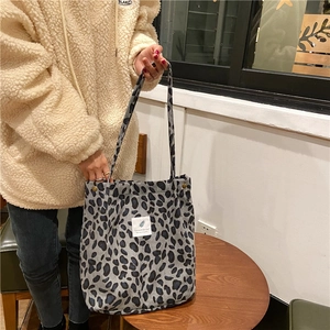Close-up of leopard print corduroy tote bag with label in a cozy cafe setting