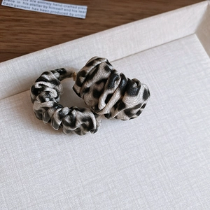 Close-up of leopard print resin earrings with pleated texture and silver needle pins