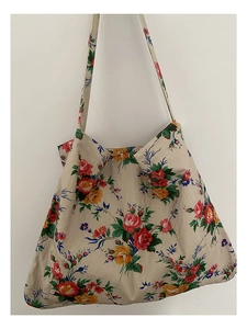 Close-up of beige canvas tote bag featuring vibrant red, yellow, and blue floral patterns