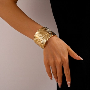 Detailed close-up of golden leaf-shaped open cuff with intricate texture on wrist