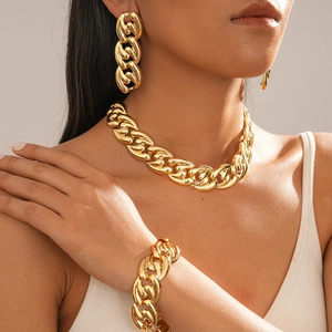 Close-up of golden bold chain necklace and bracelet set on model with metallic finish