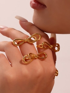 Detailed close-up of a three-piece gold bow ring set on a model's hand with mirror finish