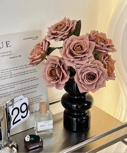 Detail of vintage pink silk roses in a black tiered ceramic vase for table decoration