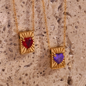 Detailed macro view of heart-shaped zircon pendants in red and purple on gold chains