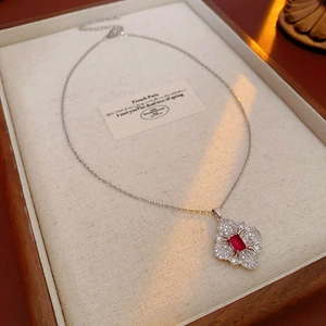 Detailed view of silver flower necklace with red gemstone and sparkling rhinestones