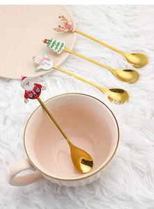 Detailed view of 4 golden Christmas spoons with Santa and reindeer cartoon charms