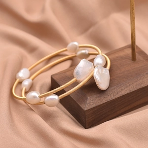 Detailed macro of baroque freshwater pearls on handcrafted golden multi-wrap wire bracelet