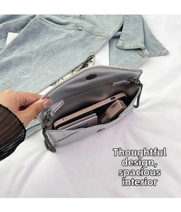 Detail view of silver envelope bag showing spacious interior and skull relief flap
