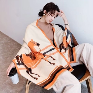 Close-up of elegant orange scarf with horse print and stripes worn by a fashion model