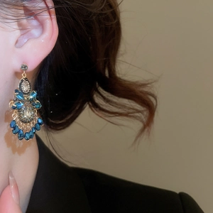 Detailansicht luxuriöser Quastenohrringe mit blauen Kristallen am Modell im Retro-Stil