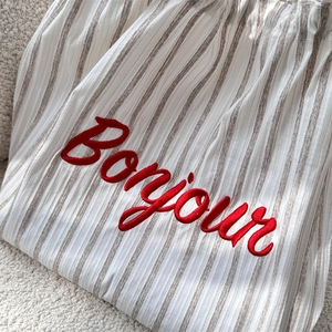 Detail showing red Bonjour embroidery and brown stripes on high-quality canvas fabric