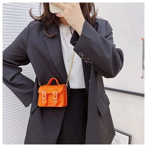Micro mini bright orange crossbody bag with gold chain strap on black blazer outfit