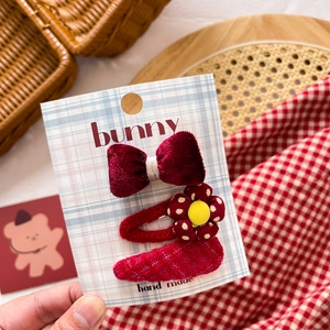 Close-up of a 3-piece red fabric hair clip set including velvet bow and knitted flower